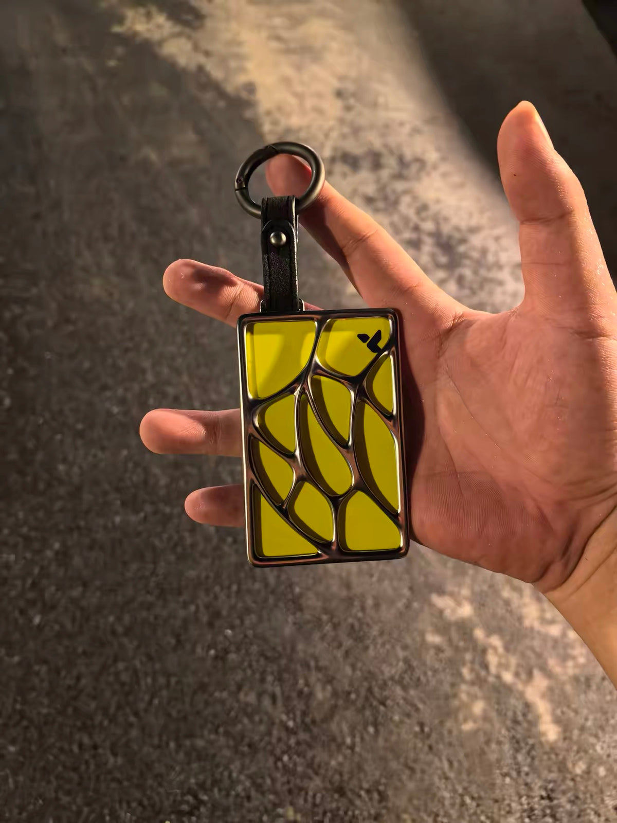 Apex metal NFC key holder in a yellow finish, held outdoors
